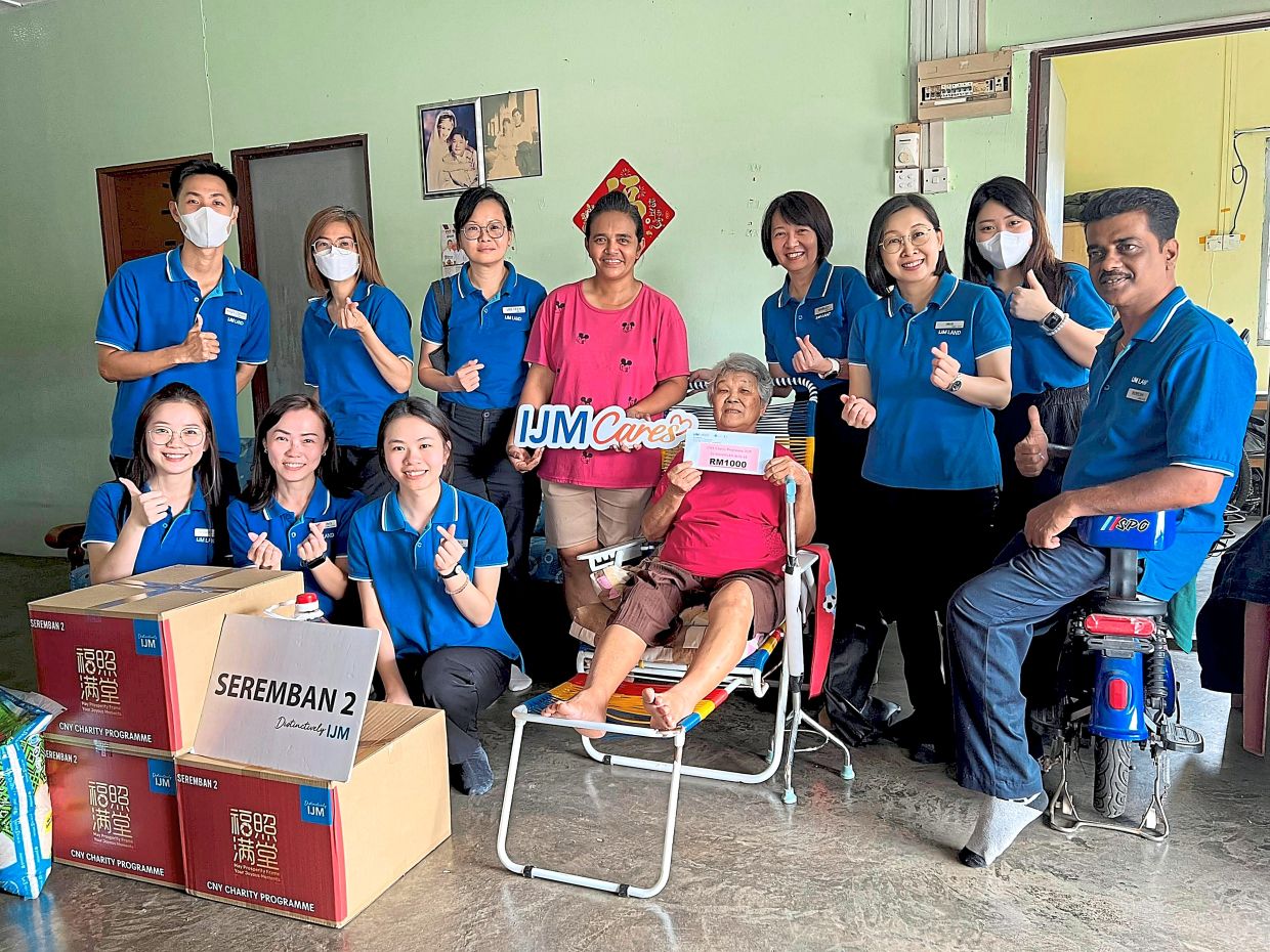 Festive cheer arrives for Wong (standing, in pink T-shirt) and a family member, courtesy of the IJM Seremban 2 team.