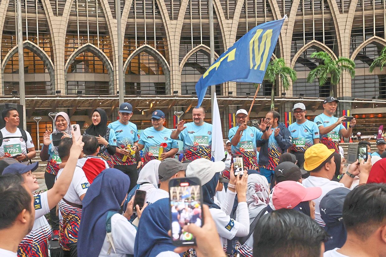 Get set, ready, go: Amir Hamzah (fifth from right) waving off runners for the 5km category at the Larian Asean: Trek Kewangan @MOF event in Putrajaya. — Bernama