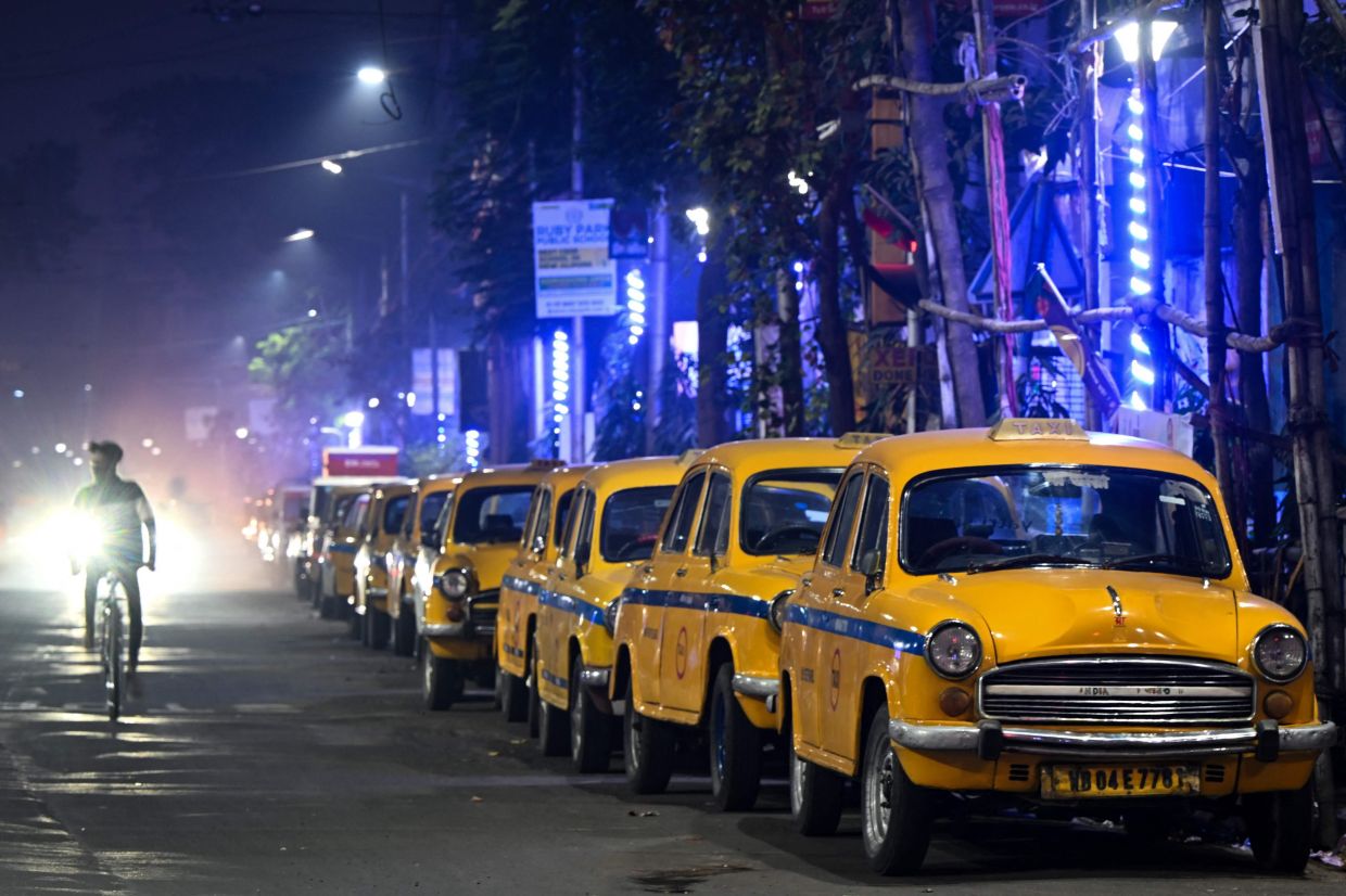 Hindustan Ambassador yellow taxis parked along a roadside in Kolkata.