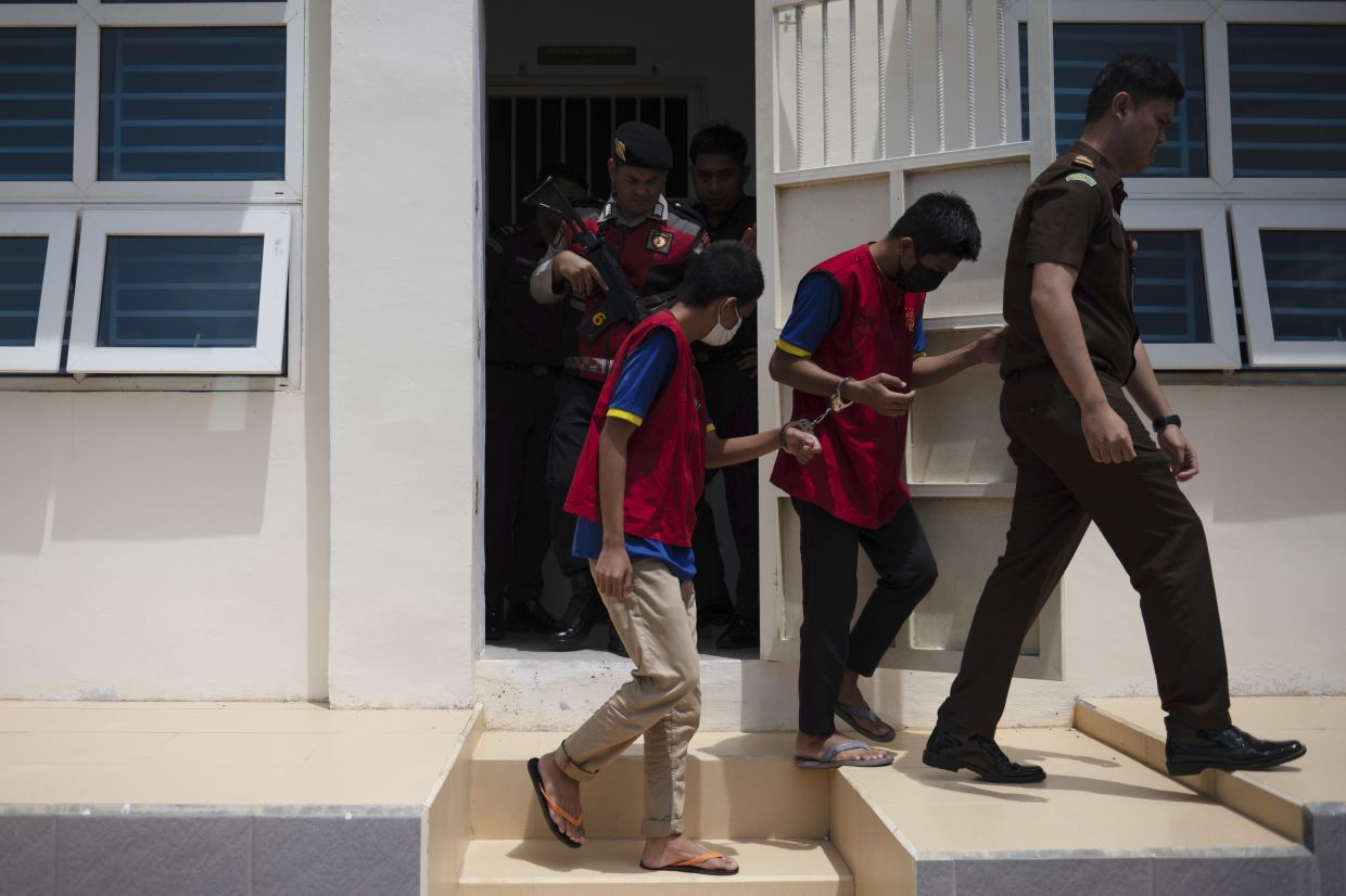 Officer escorts two gay men out of a holding cell for the start of their trial at Sharia court in Banda Aceh, Indonesia, Monday, Feb 24, 2025. -- AP Photo/ Reza Saifullah