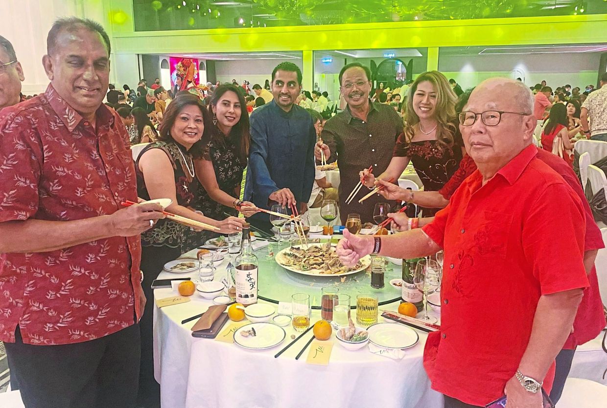 Chan (fifth from left) and Azmin (on his right) with guests tossing ‘yee sang’ at the start of the Chinese New Year dinner.
