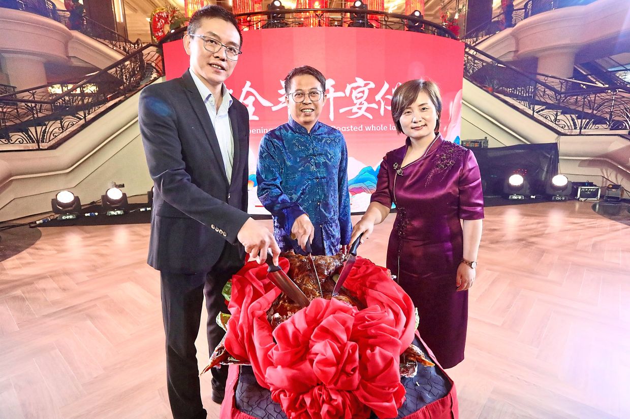 (From left) Yau, Lee and Yang cutting the roast lamb during the gala dinner in IOI Resort City.