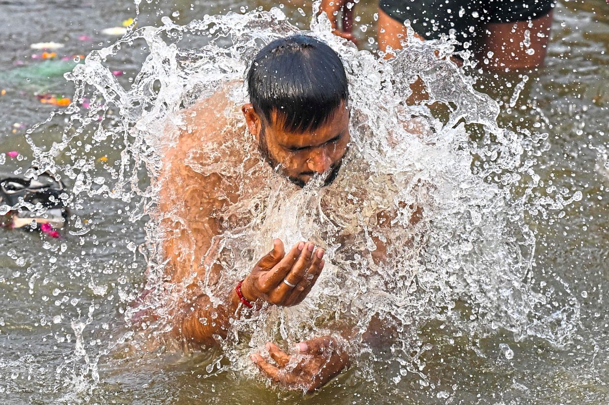Sacred rituals: A pilgrim taking a holy dip in Sangam, the confluence of Ganges, Yamuna and mythical Saraswati rivers. — AFP/AP