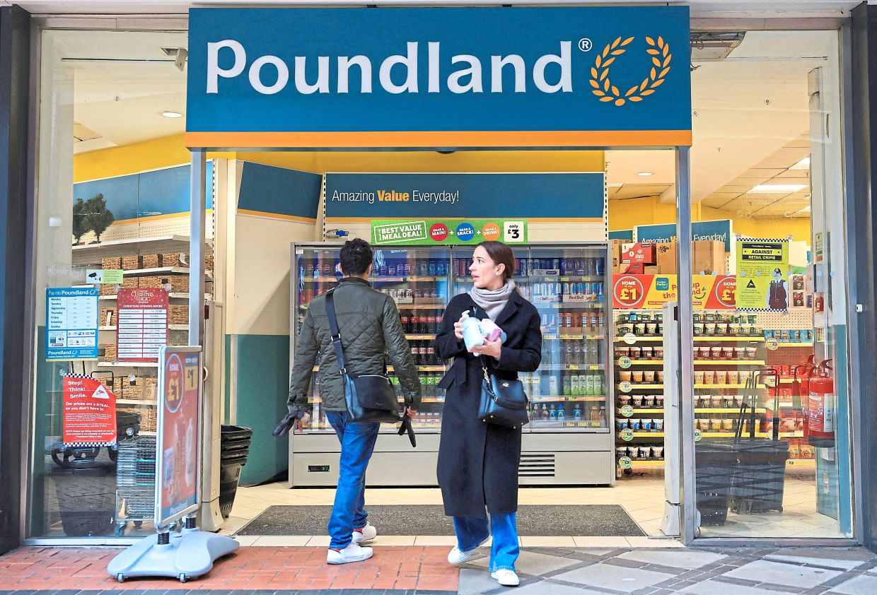 A file photo of shoppers walking by Poundland in London. — Reuters 