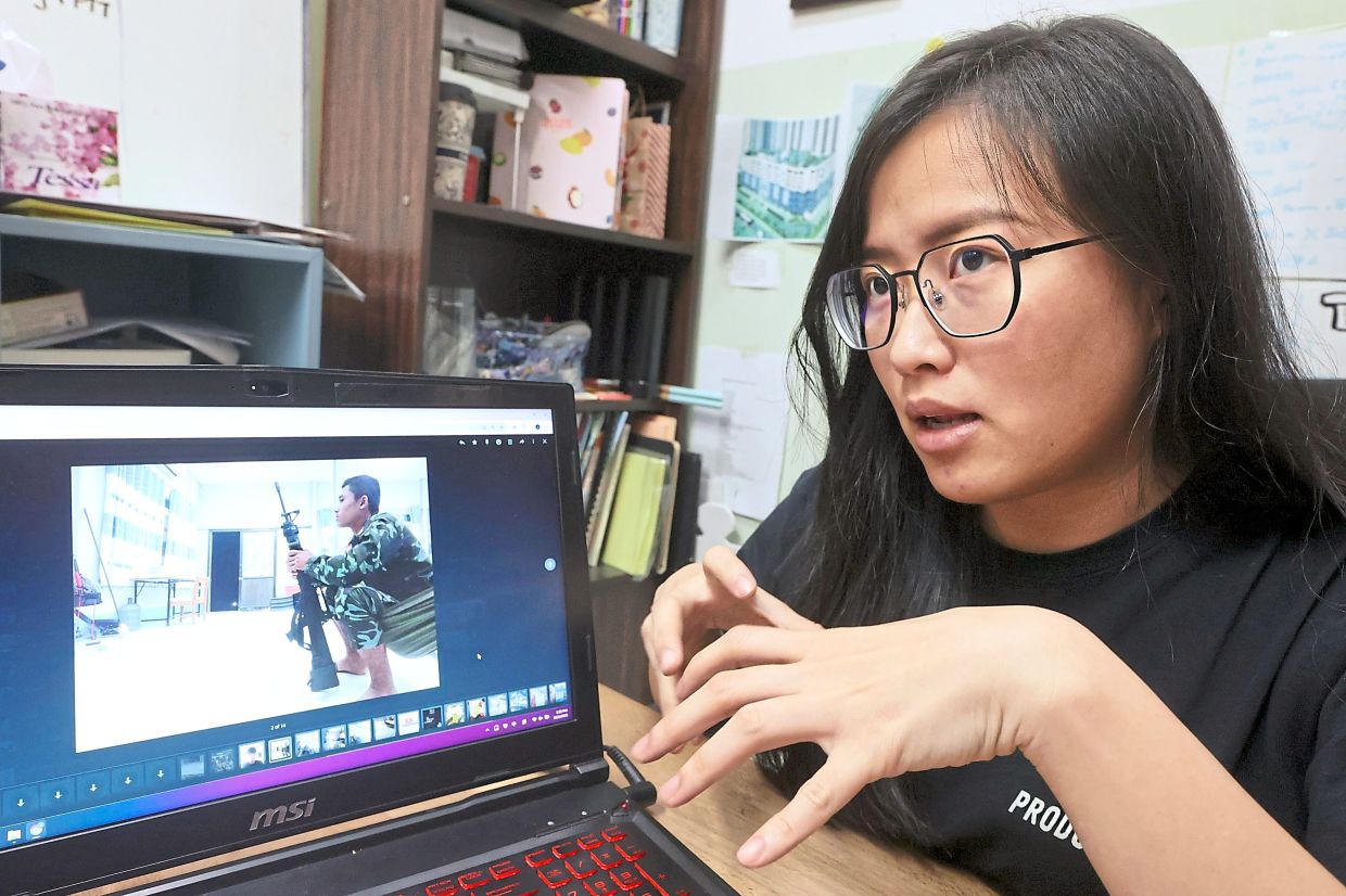 Dangerous situation: Hwang showing some of the pictures Gan sent to her, including one of an armed man on guard. — THOMAS YONG/The Star