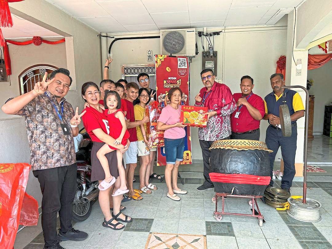 Mydin area coordinator Kuldipjeet Singh handing over a box of mandarin oranges to competition winner Tiong Wue Peang in the presence of her family and his team in Teluk Intan, Perak on Jan 30.