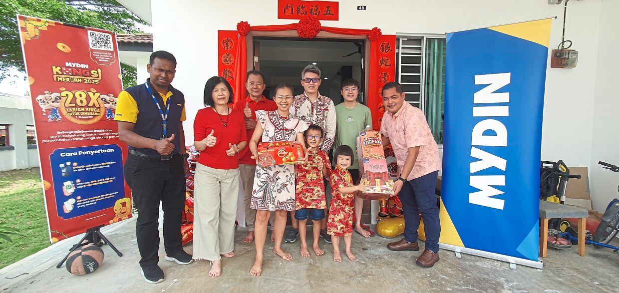Competition winner Tan Yee Lian (centre) together with her family, Mydin Mutiara Rini branch manager S. Mohan (left) and Mydin Johor branch area coordinator Nik Azahari Nik Asmady (right) posing for a group photo after receiving her gift of a free lion dance performance at her home in Johor Baru on Feb 1.