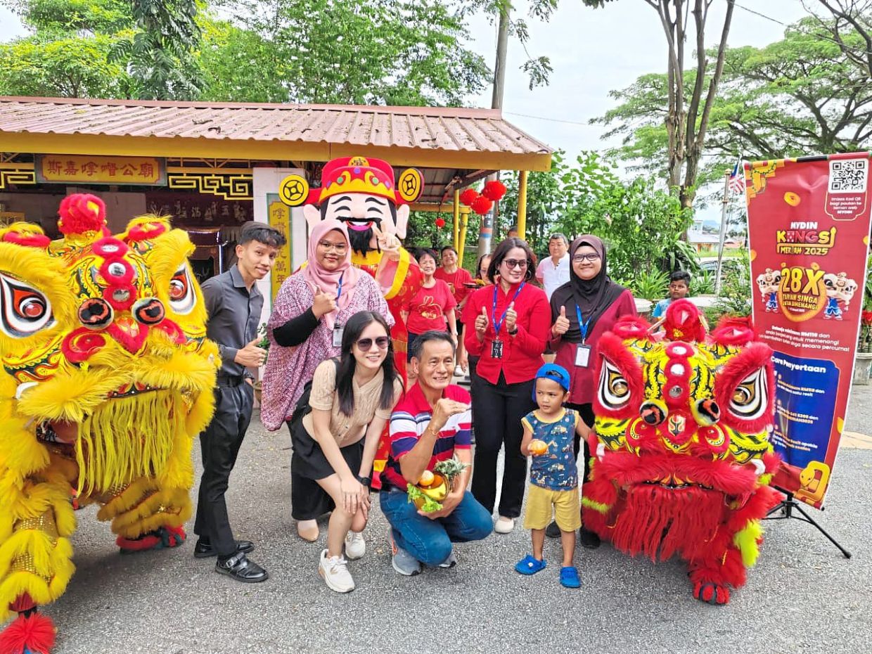 Competition winner Goh Eng Guan (centre) and his family posing with Mydin Selayang branch manager S. Ruby Saral and department manager Wan Nor Zila Wan Sulaiman before the lion dance performances in Batu Caves, Gombak, Selangor on Feb 2.