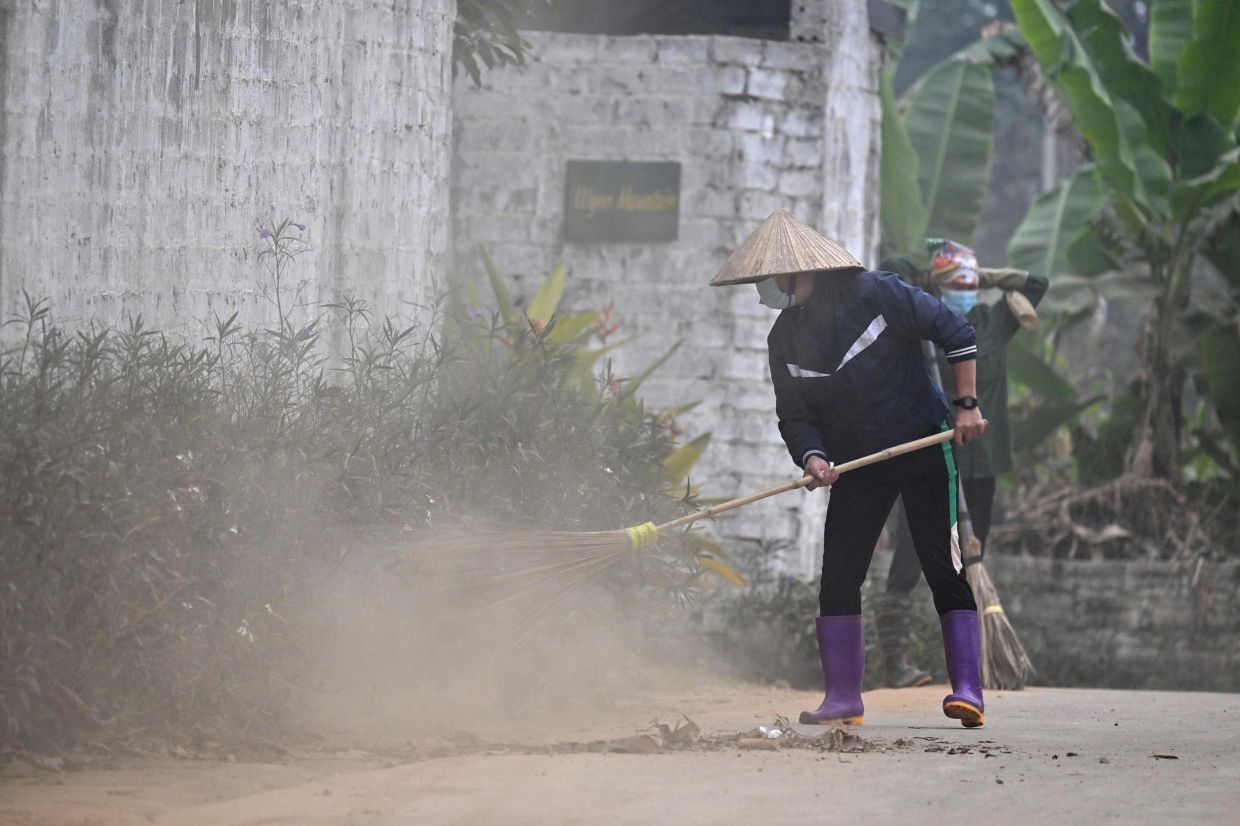 A worker sweeping dust amid air pollution in a village on the outskirts of Hanoi. In the last three months, the Vietnamese capital has regularly topped a list of the world's most polluted major cities, leaving its nine million residents struggling to breathe and even to see through a thick blanket of smog. -- Photo by Nhac NGUYEN / AFP
