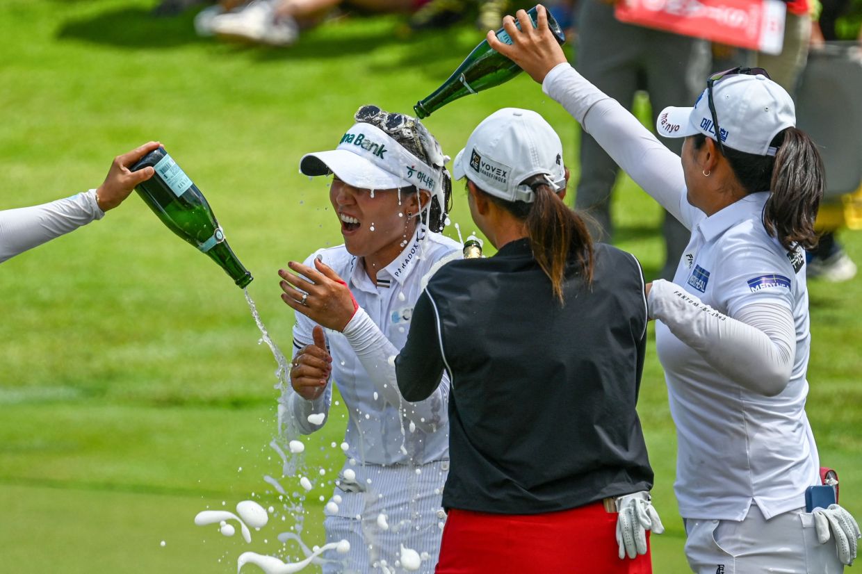 Lydia Ko of New Zealand (centre) celebrates with champagne and fellow players after winning the HSBC Women's Championship golf tournament at Sentosa Golf Club in Singapore on March 2, 2025. - Photo by Roslan RAHMAN / AFP