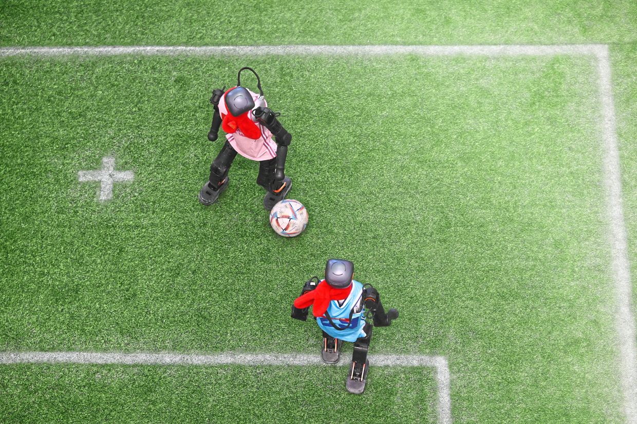 Machines on the field: Robots vying for the ball during an exhibition football match at the fair in Beijing. — AFP