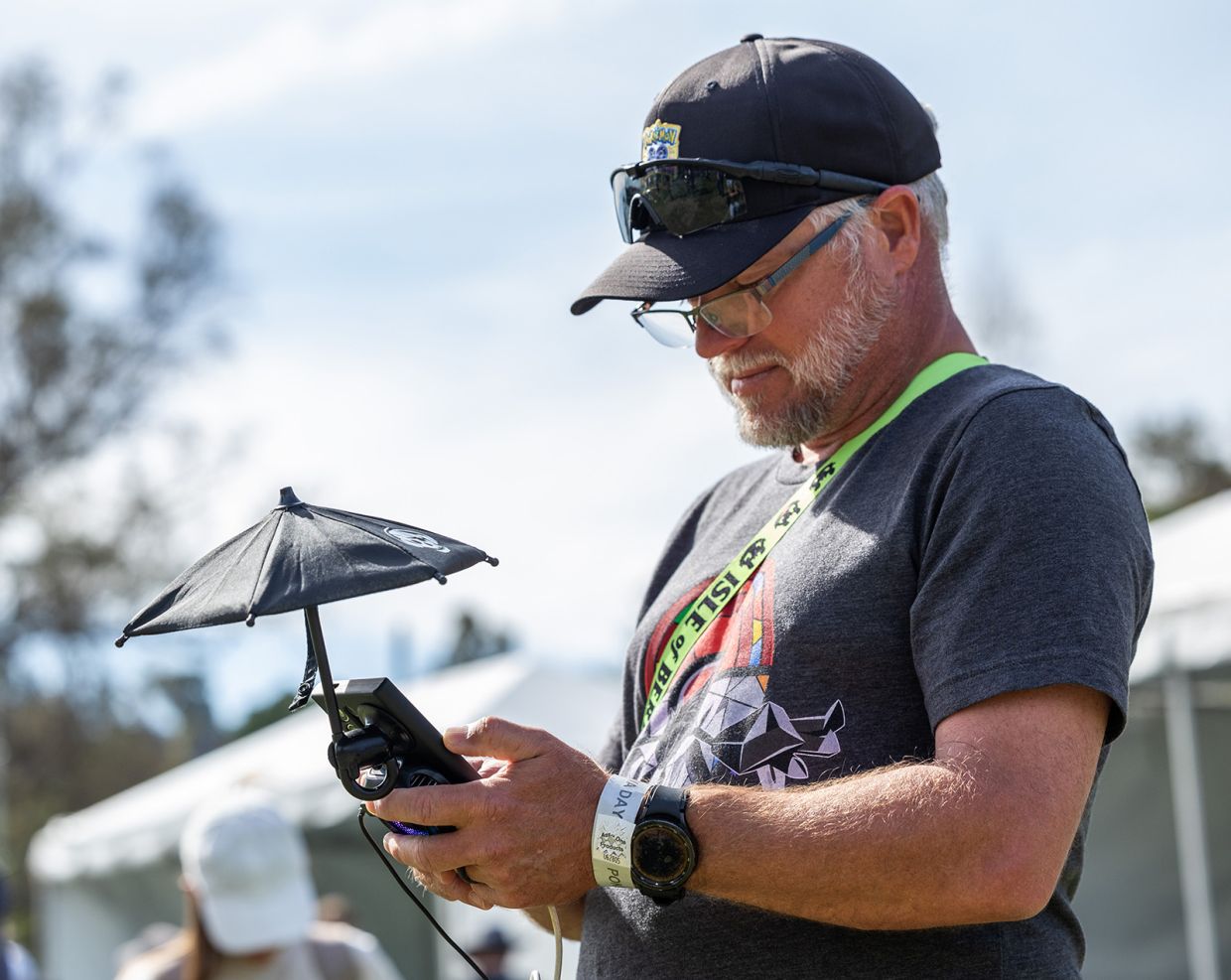 Mike Simmons of Florida uses an umbrella to better see his screen while collecting Pokemon during the Pokemon GO Tour: Unova Los Angeles at the Rose Bowl in Pasadena, CA on Saturday, Feb 22, 2025. — Los Angeles Times/TNS