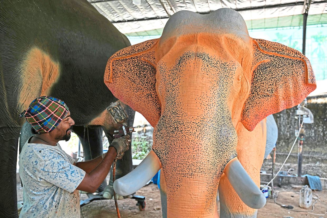 A worker painting a robotic elephant model. 