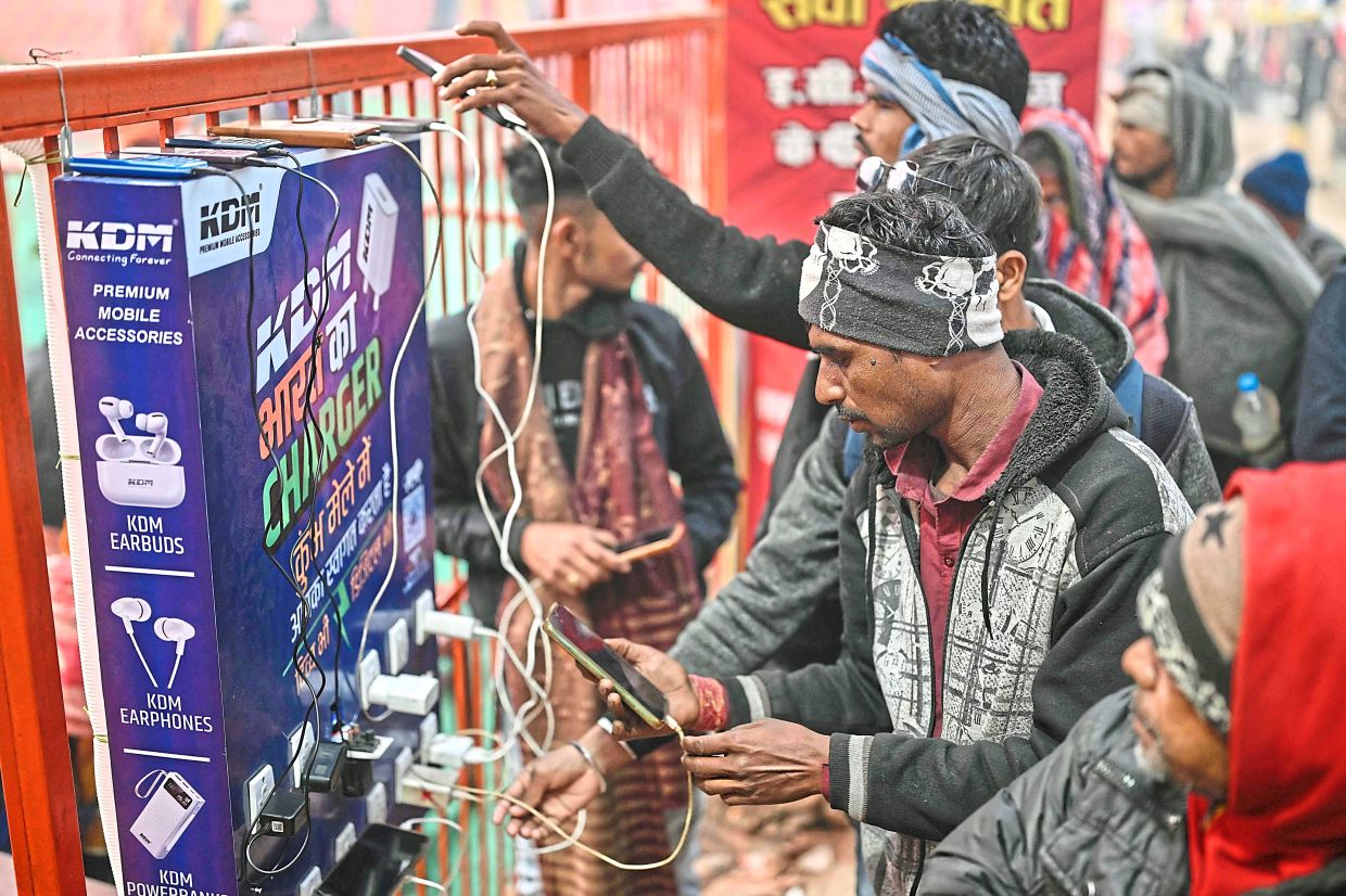 Hindu pilgrims charging their mobile phones at a charging point at the festival. — AFP