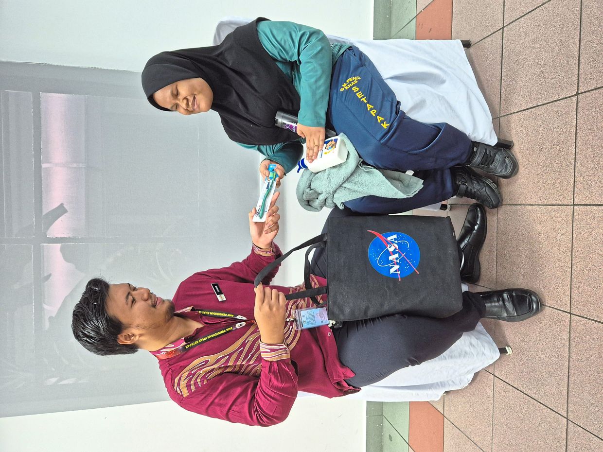 Siti Nursuhaila proudly showing her new school supplies to her teacher, Mohd Ikhwan Suhaimi.