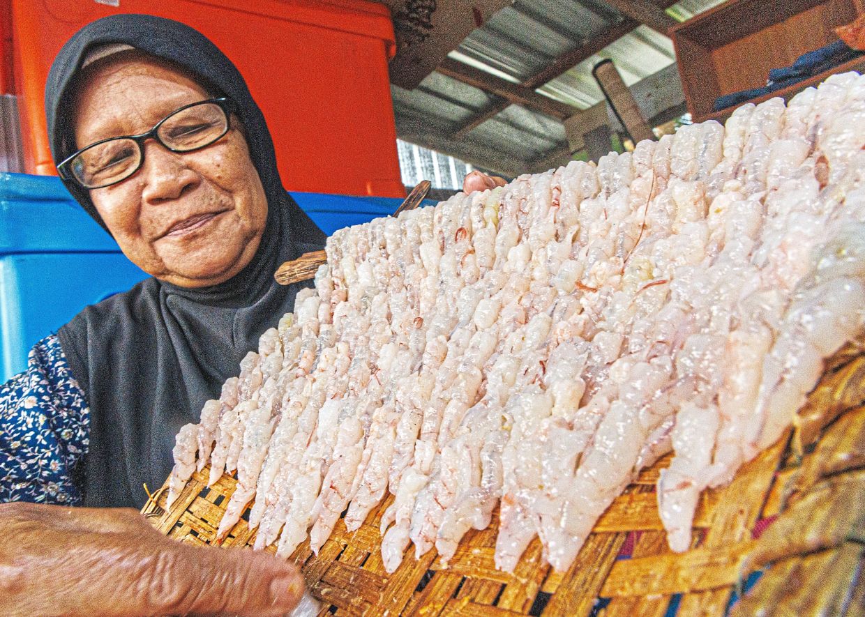 Masni, who has been making ‘sesar unjur’ since her teens, holding up a ‘kilak’ full of shrimps.