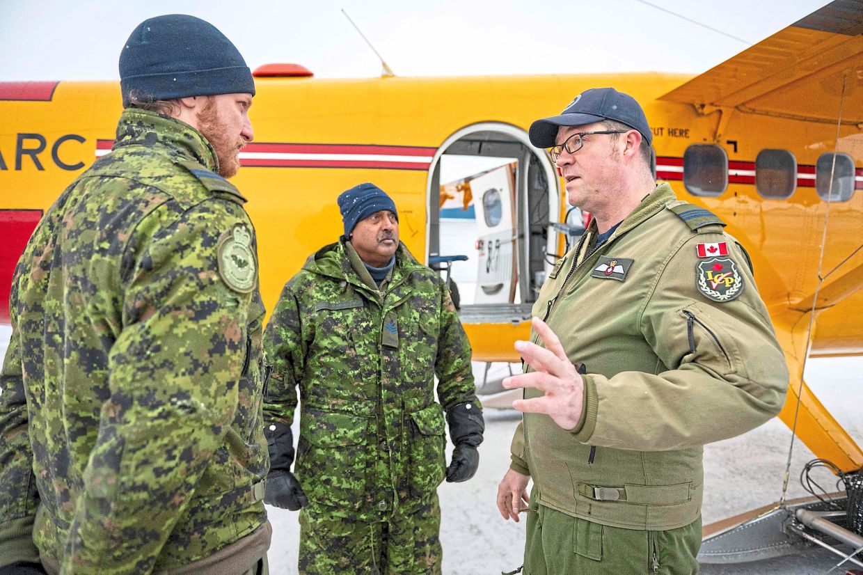 Major Mongeon (right) speaking with crew members before a flight at Yellowknife Airport, Northwest Territories, Canada. — AFP