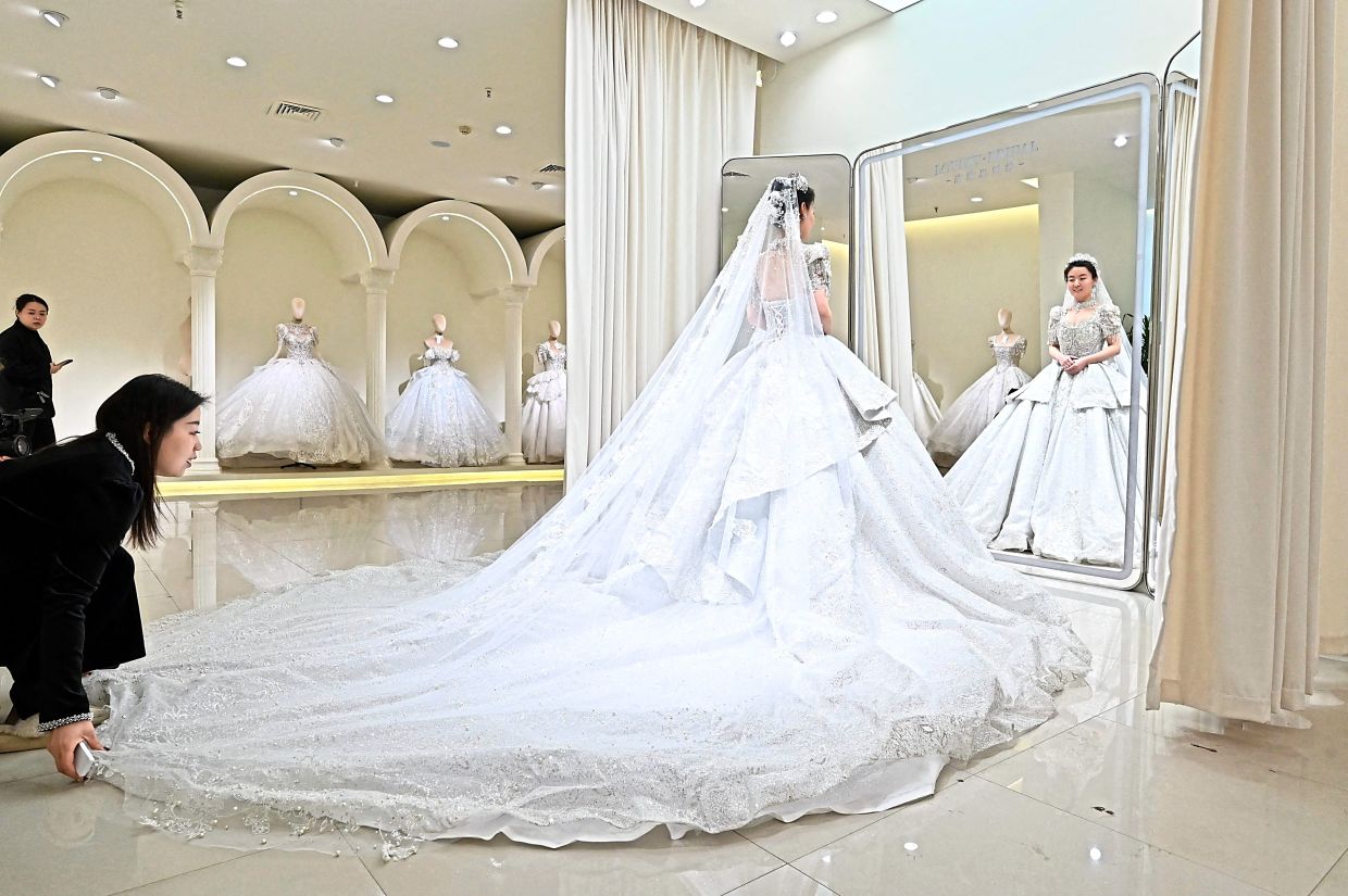 Wedding fever: A woman doing a bridal fitting at a bridal shop in Luliang. — AFP