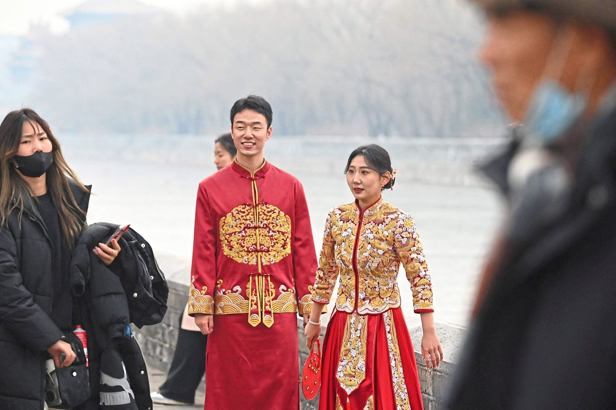 Snapshots of a lifetime: A couple waiting during a wedding photoshoot outside the Forbidden City in Beijing. — AFP