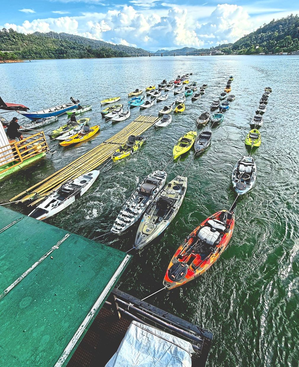 Trains of kayaks being towed behind a boathouse.