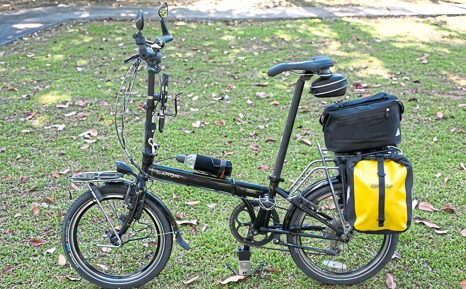 A folding bike rigged for touring with a set of Ortlieb front roller panniers and a trunk bag.