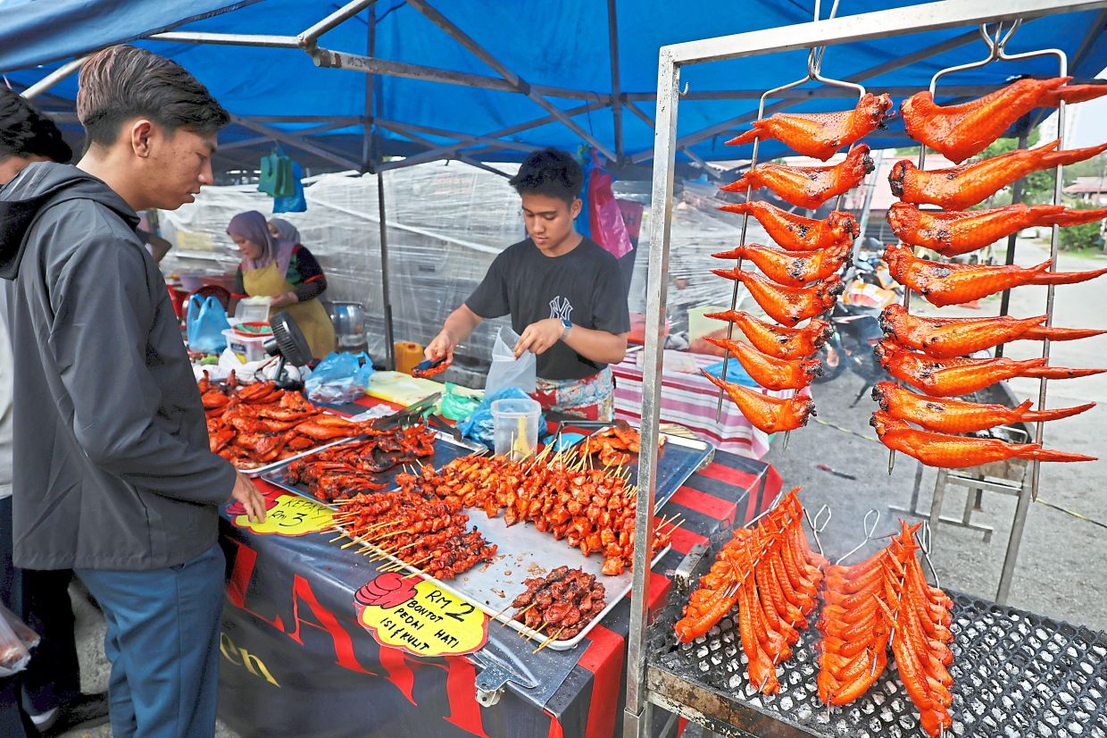 A trader packing grilled chicken for customers at the bazaar.