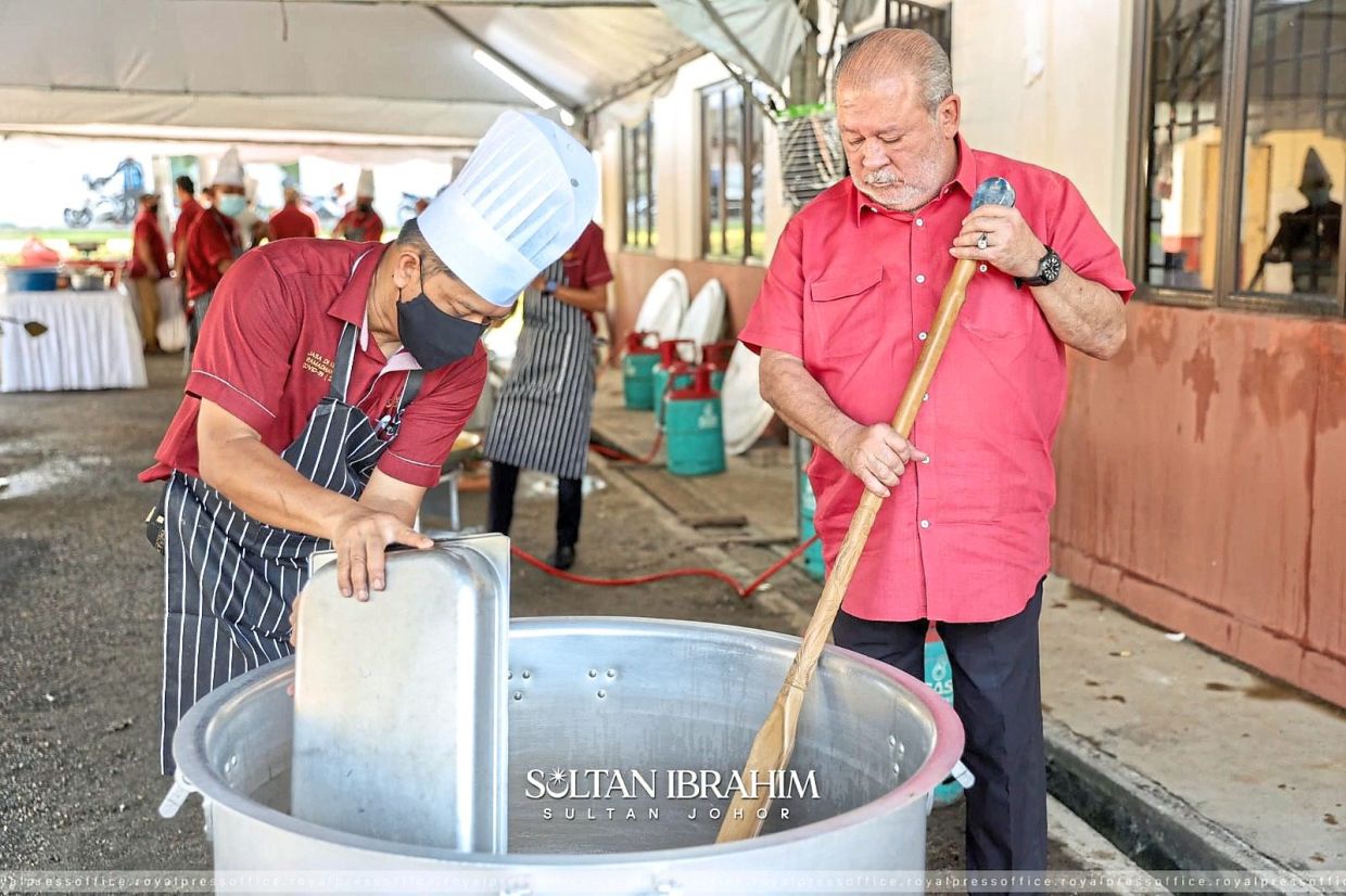 Sultan Ibrahim stirring a pot of bubur lambuk with a custom-made wooden spatula
