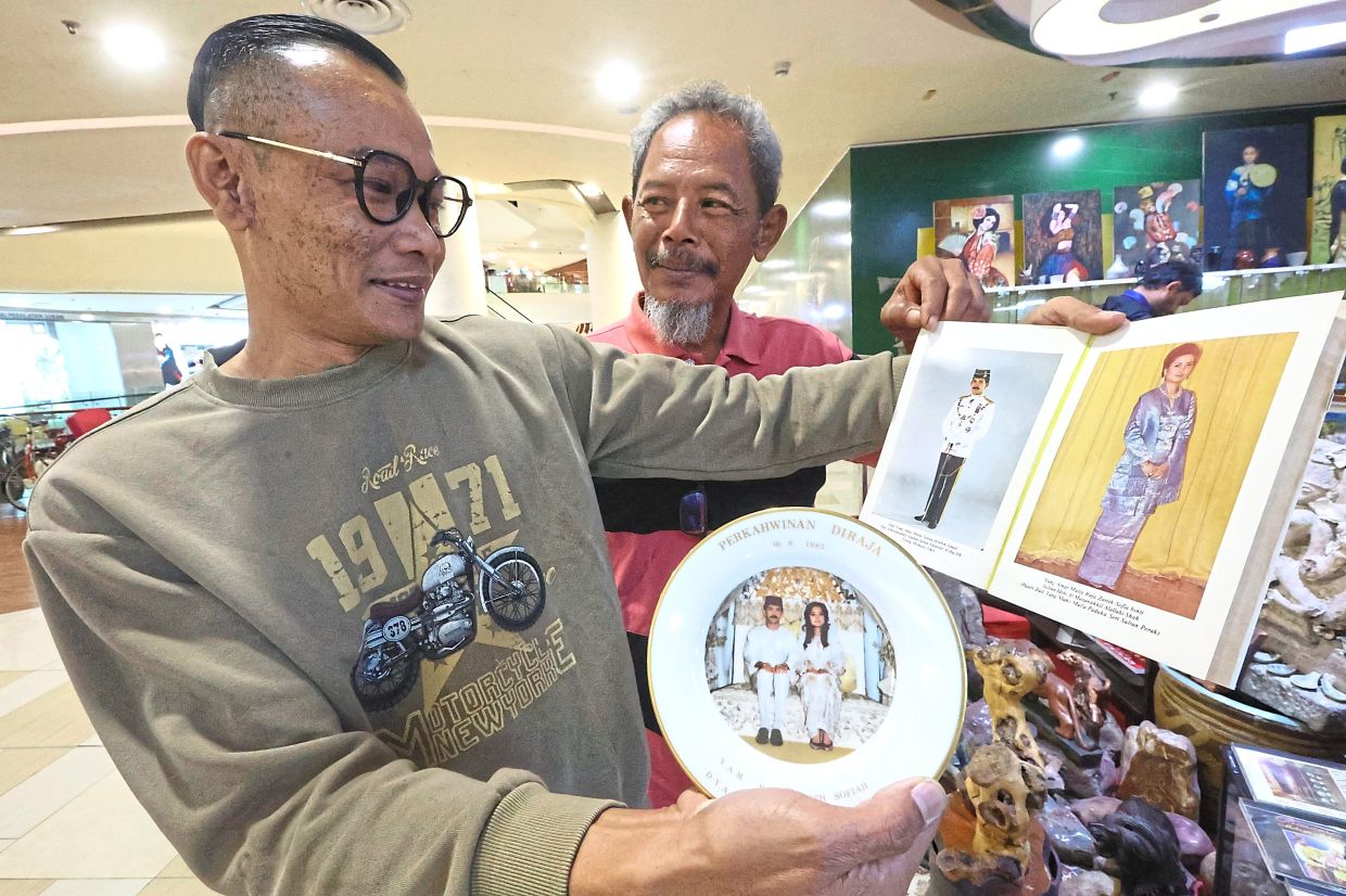 Mohd Faris (left) showing visitor Borhan Samyon a book and plate commemorating the marriage between Sultan Ibrahim and Permaisuri Johor Raja Zarith Sofiah Binti Almarhum Sultan Idris Shah, at the Johor Historical Gallery in Johor Baru.