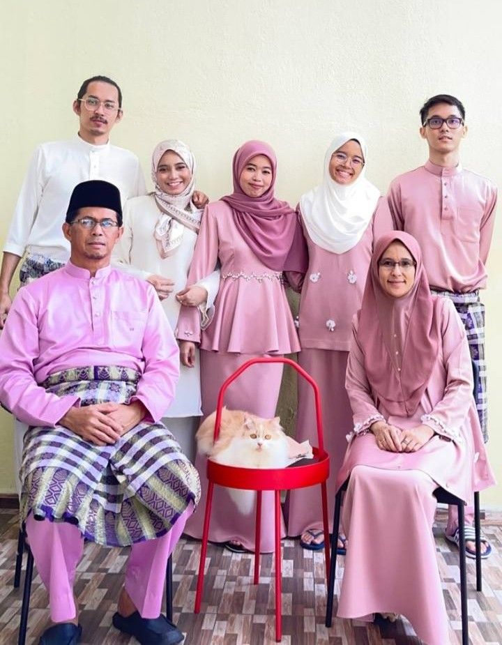Raziah (seated, right) with her family husband and grown-up children, who now carry the tradition of giving duit raya. Photo: RAZIAH OSMAN