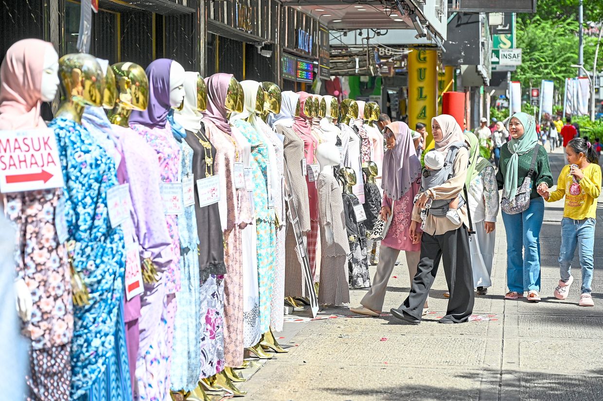 A family admires an array of colourful baju kurung displayed outside a shop along Jalan Tuanku Abdul Rahman in Kuala Lumpur.