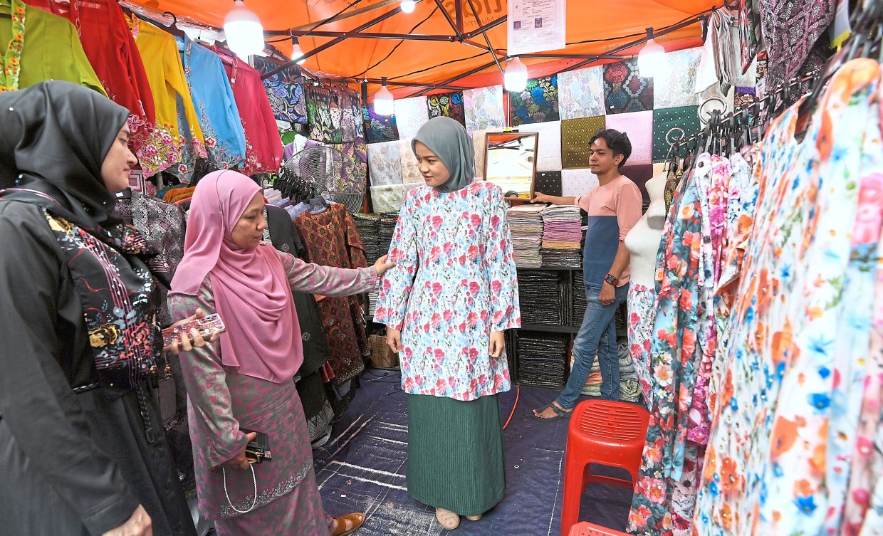 A shopper tries on a ‘baju kurung’ at a Bazaar Aidilfitri stall.