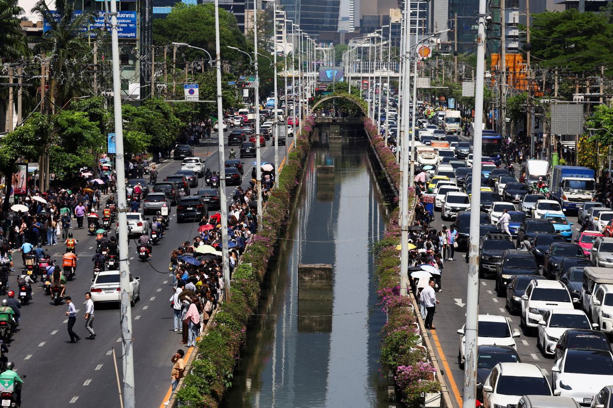 People stand on the road as cars are stuck in traffic after a strong earthquake struck central Myanmar on Friday, earthquake monitoring services said, which affected Bangkok as well with hundreds of people pouring out of buildings in the Thai capital in panic after the tremors, in Bangkok, Thailand, on Friday, March 28, 2025. -- REUTERS/Photo: Athit Perawongmetha