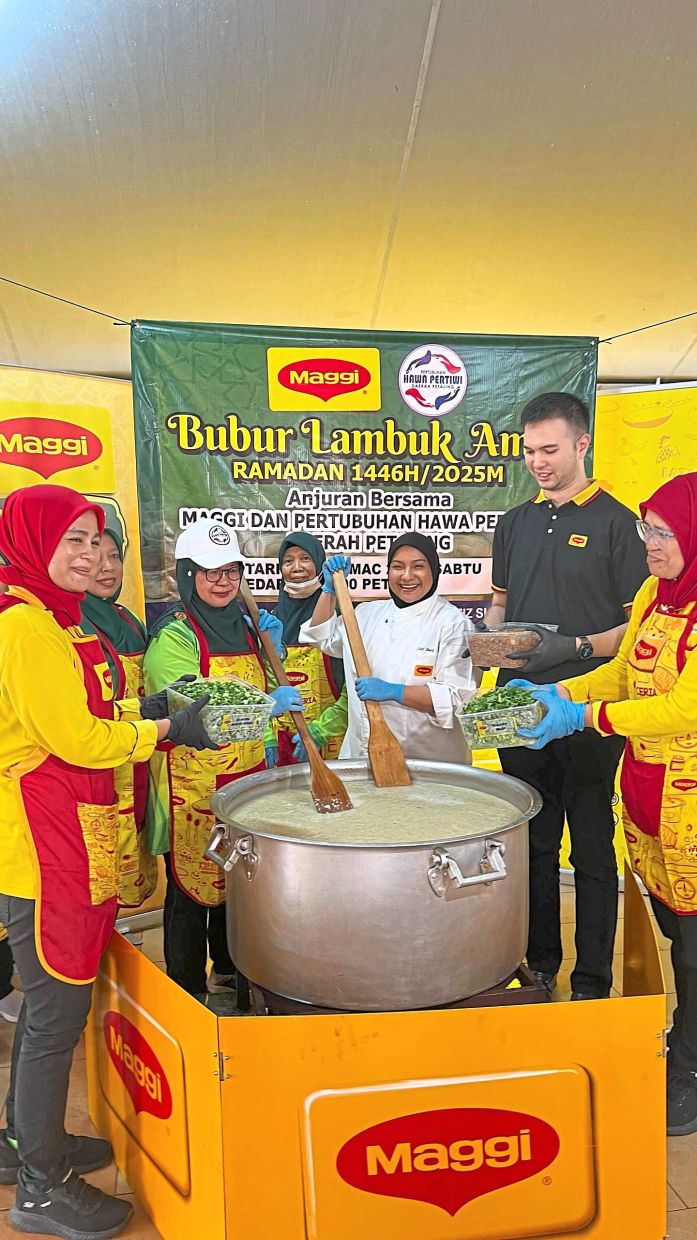 Chef Sharifah (third from right) with some participants helping to prepare the bubur lambuk.— Photos: CHAN TAK KONG/The Star