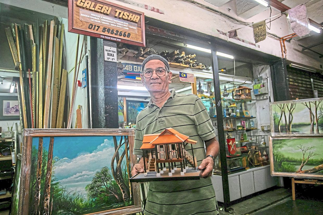 Saari holding a replica house at Galeri Tisha. He also does oil paintings. 