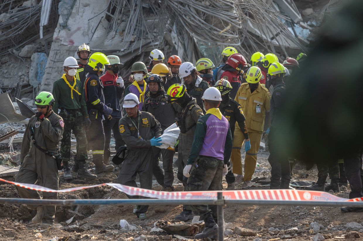 Rescue workers extract the body of a construction worker from the rubble of a building that collapsed following an earthquake in Bangkok, Thailand, Saturday, March 29, 2025. Rescuers are still searching for dozens of people missing from the site of the high-rise building, which was under construction when it collapsed after a 7.7-magnitude earthquake struck neighboring Myanmar. -- Photographer: Andre Malerba/Bloomberg