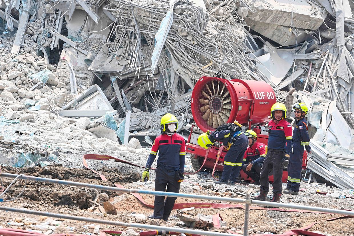Ongoing mission: Rescuers working at the damaged construction site in Bangkok. — AP