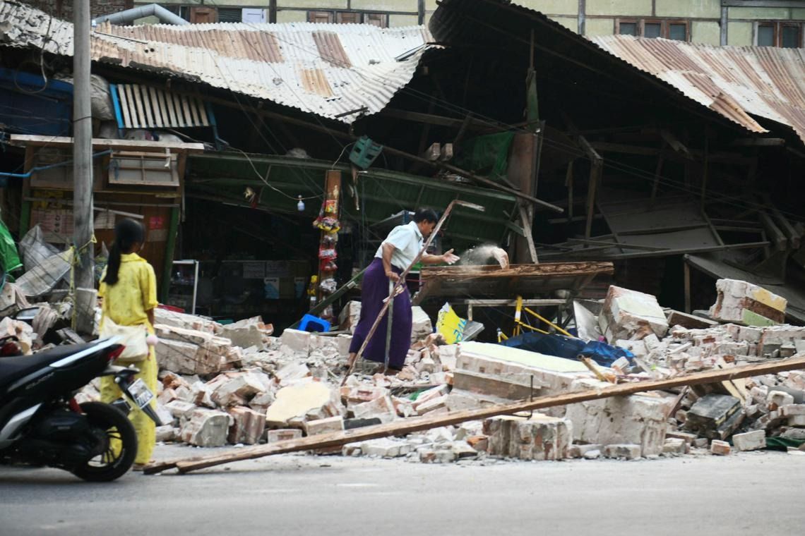 A resident clearing debris in front of damaged houses after a 7.7-magnitude quake devastated the city of Mandalay in Myanmar on March 30, 2025. - Photo: AFP
