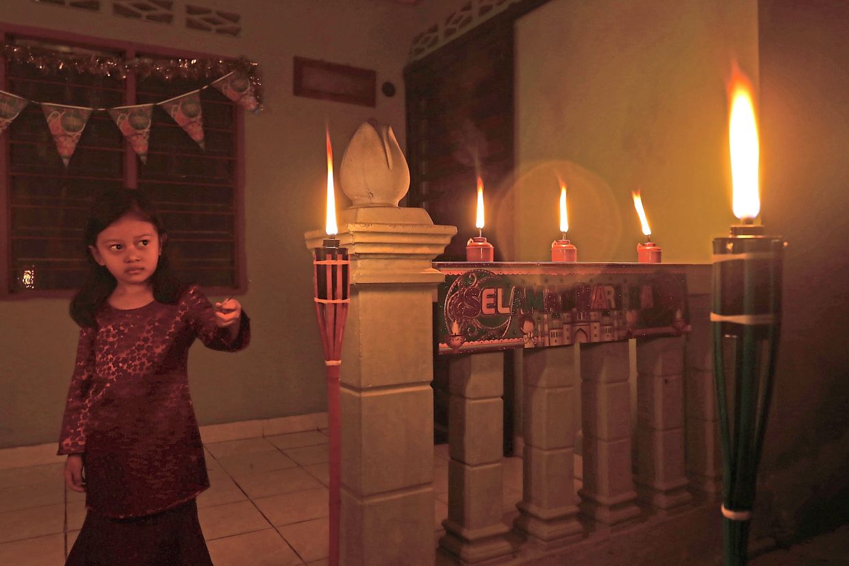 A child is mesmerised by the glow of ‘pelita’ decorating the compound of her house in Rawang, Selangor, for the festive celebration.