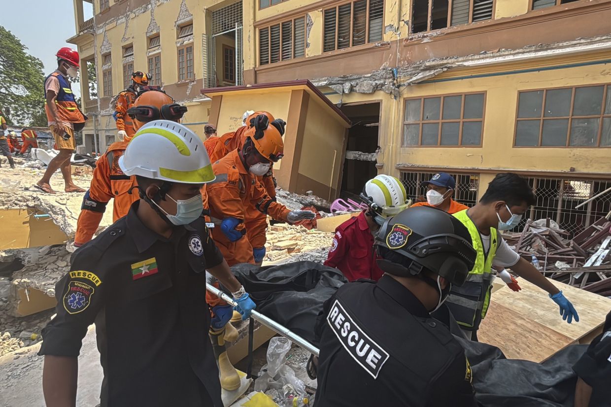 Indian and Myanmar rescuers carrying a dead body at U Hla Thein Buddhist monastery that collapsed in Friday's earthquake in Mandalay, on March 31. - AP
