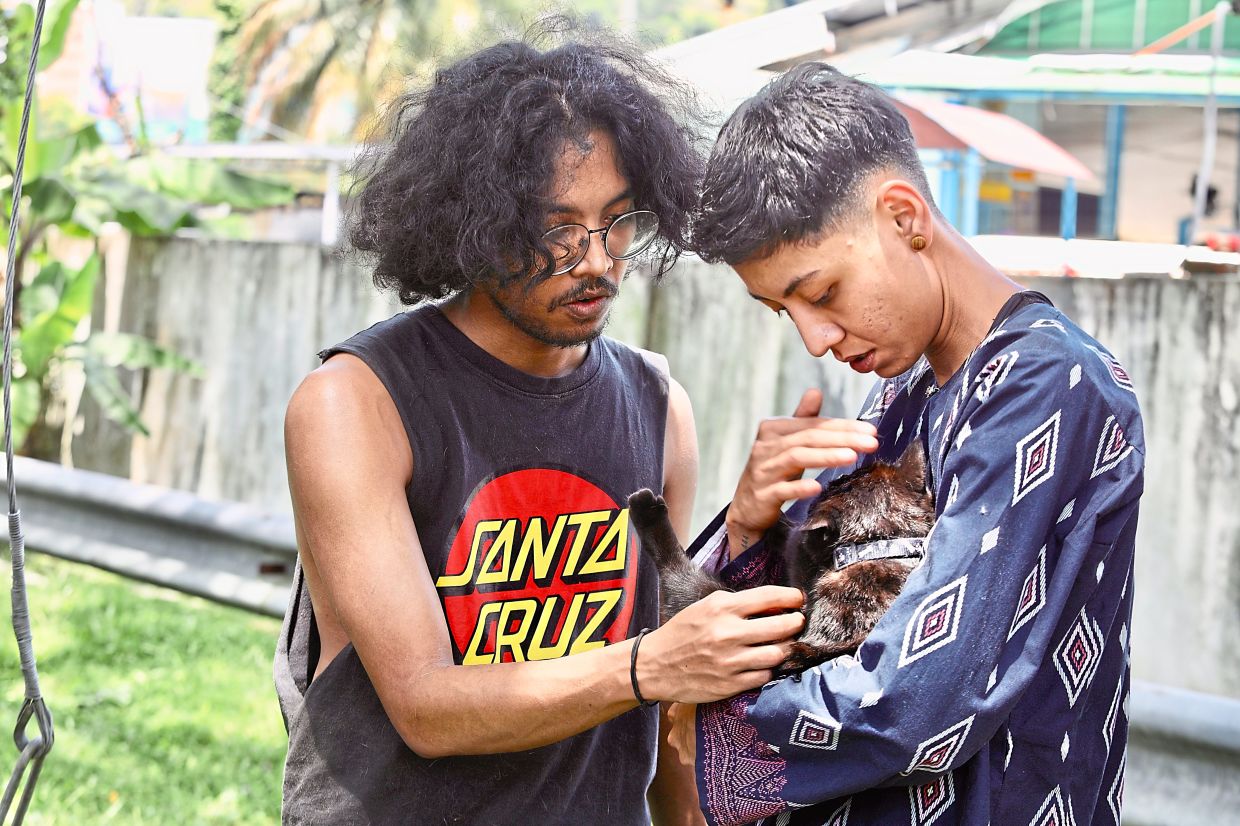 Aqiel Najmie and his sister Aina Natasya comforting their family cat following the blaze at Putra Heights. — LOW LAY PHON/The Star