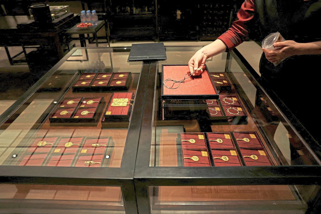 A staff member putting a gold necklace on a tray. — Reuters