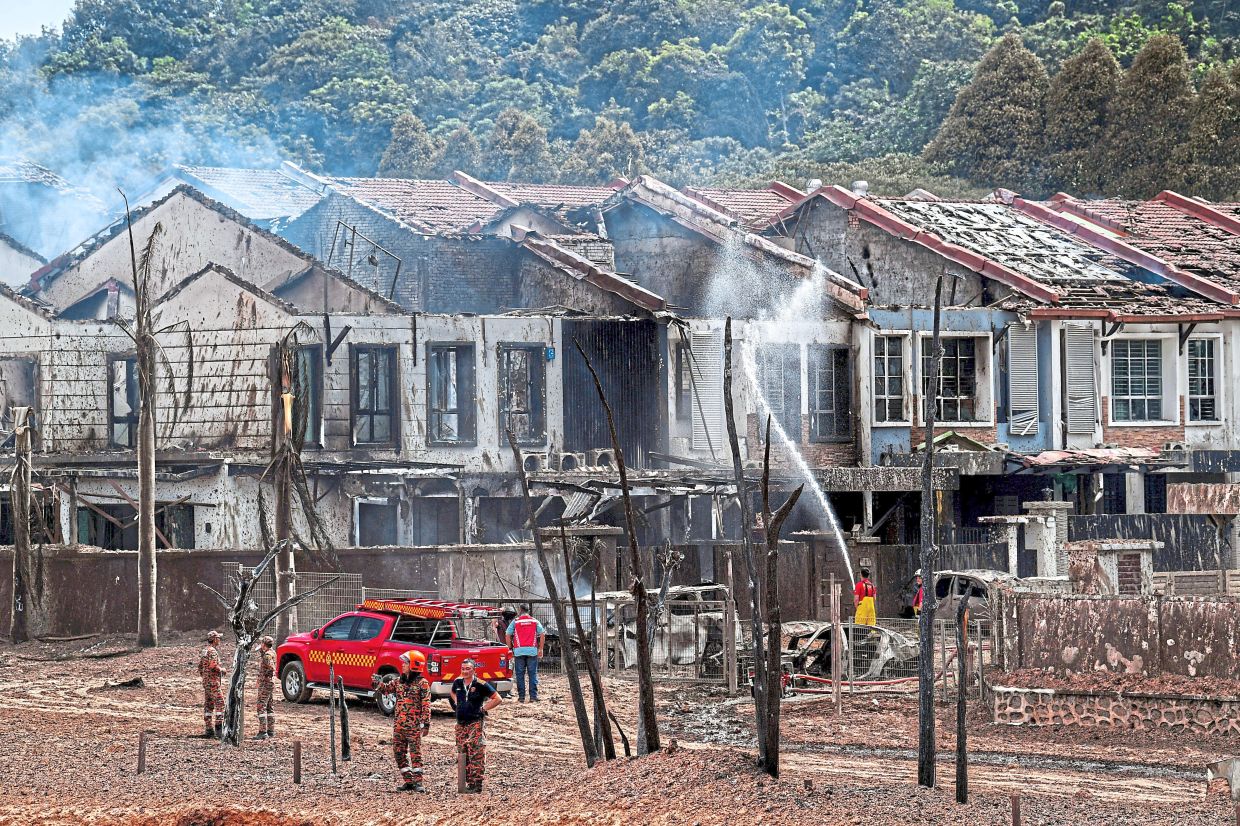 Heroes in action: Firemen dousing out flames at residences that were damaged by the blast.— Bernama
