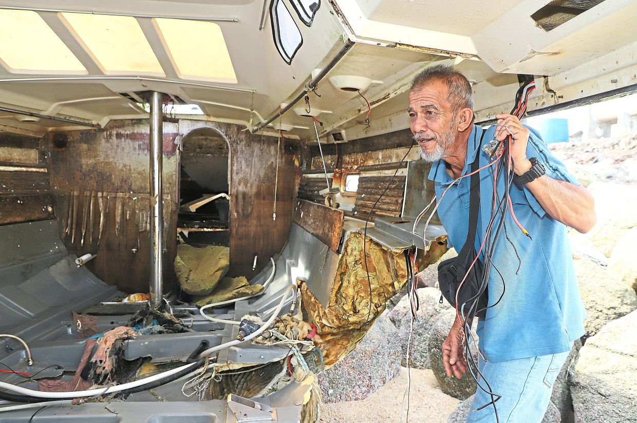 Chaotic sight: Abdul Jamil checking the interior of the damaged boat. — LIM BENG TATT/The Star 