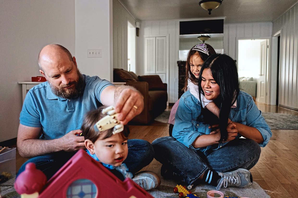 Grebow and his wife sitting on the floor of their home playing with their two children in San Gabriel, California. The realities of construction costs and insurance payments after the Eaton fire have set in for residents. — Mark Abramson/The New York Times