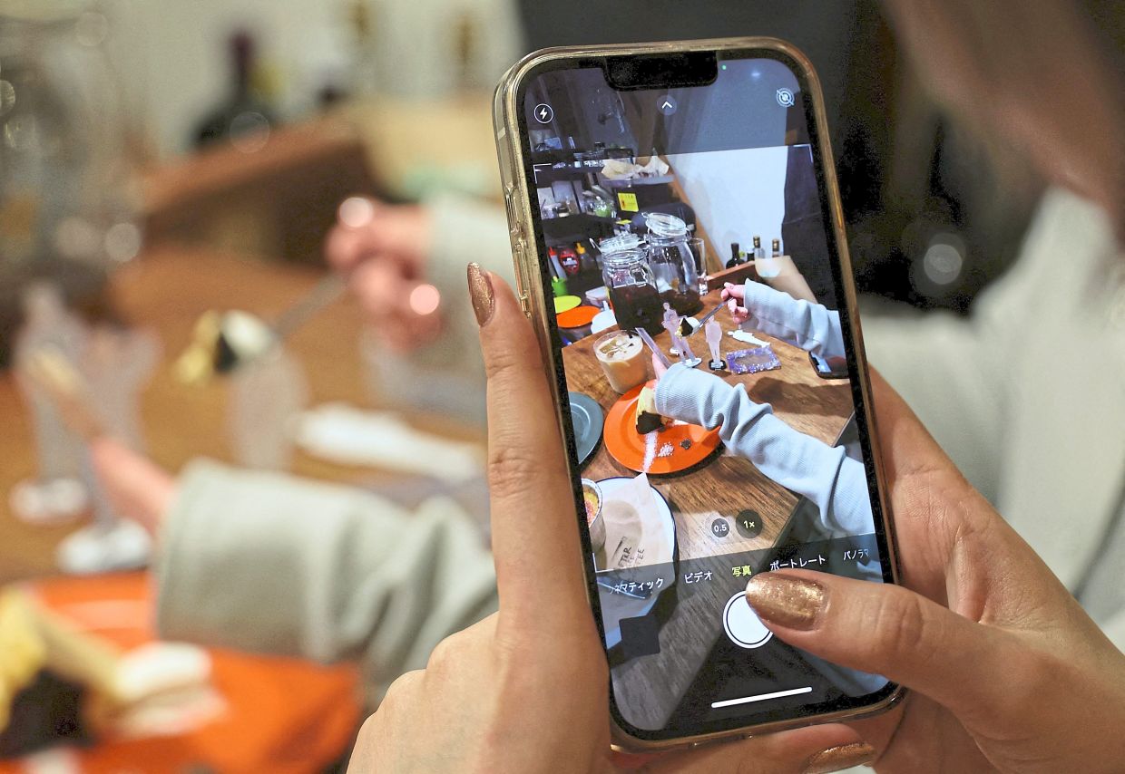 Matsui and her co-worker taking pictures of acrylic models of their idols at a cafe, where their favourite boy band once visited. 