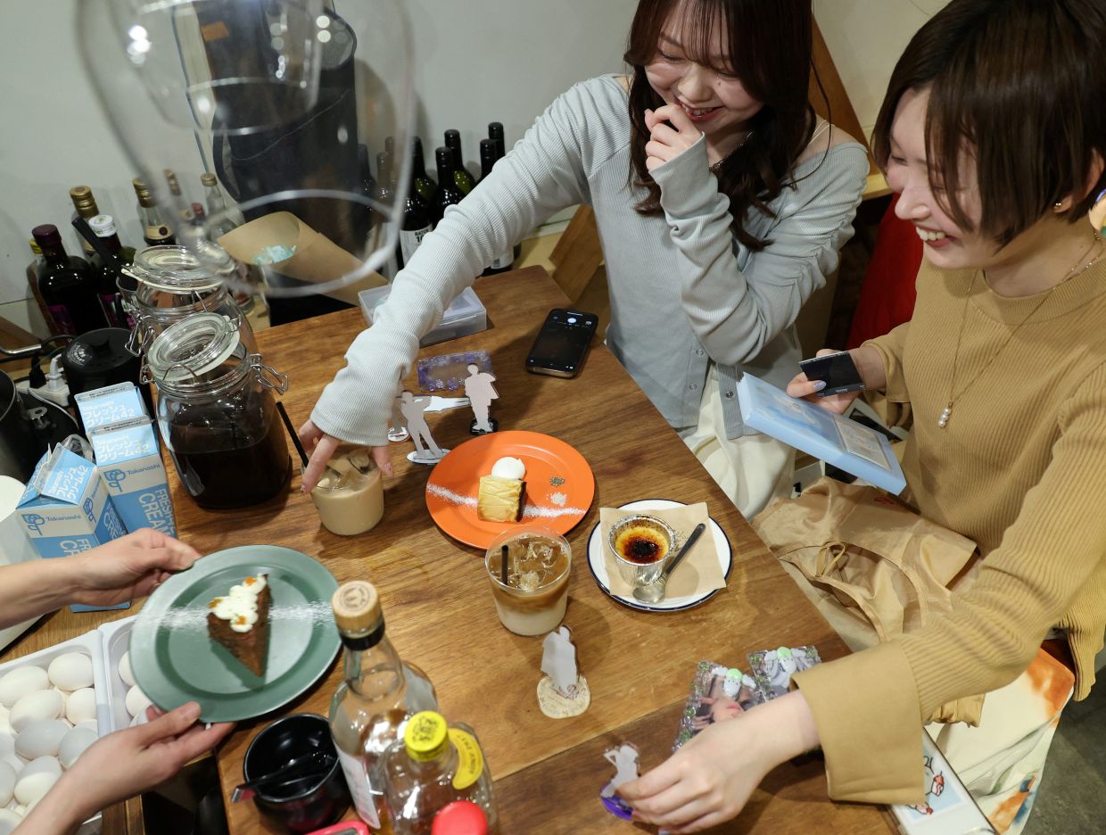 Momoka Matsui and her co-worker Saki Matsumoto prepare to take photos of acrylic stand figure models of their favorite idols with cakes and teas, which they ordered at After All Coffee, where Matsui’s favorite boy band stopped by, in Tokyo, Japan March 23, 2025. — Photo: REUTERS/Kim Kyung-Hoon