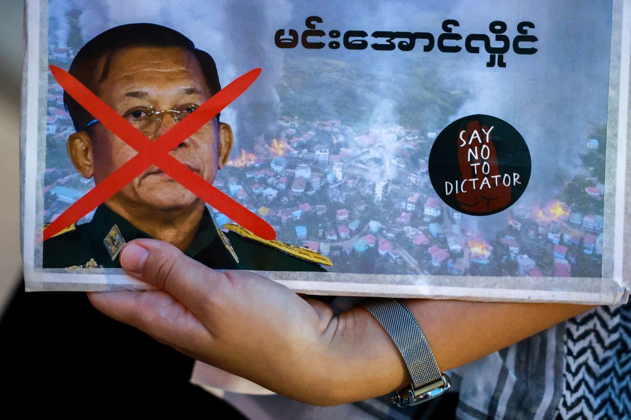 An activist holds a picture of Myanmar's junta leader Min Aung Hlaing during a protest against his visit to Thailand and attending the 6th BIMSTEC Summit in Bangkok, Thailand, on Friday, April 4, 2025. -- REUTERS/Athit Perawongmetha