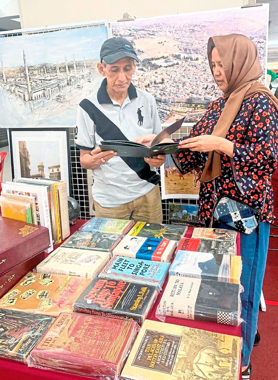 Zari (left) attending to a visitor at his booth at the flea market in Amcorp Mall.