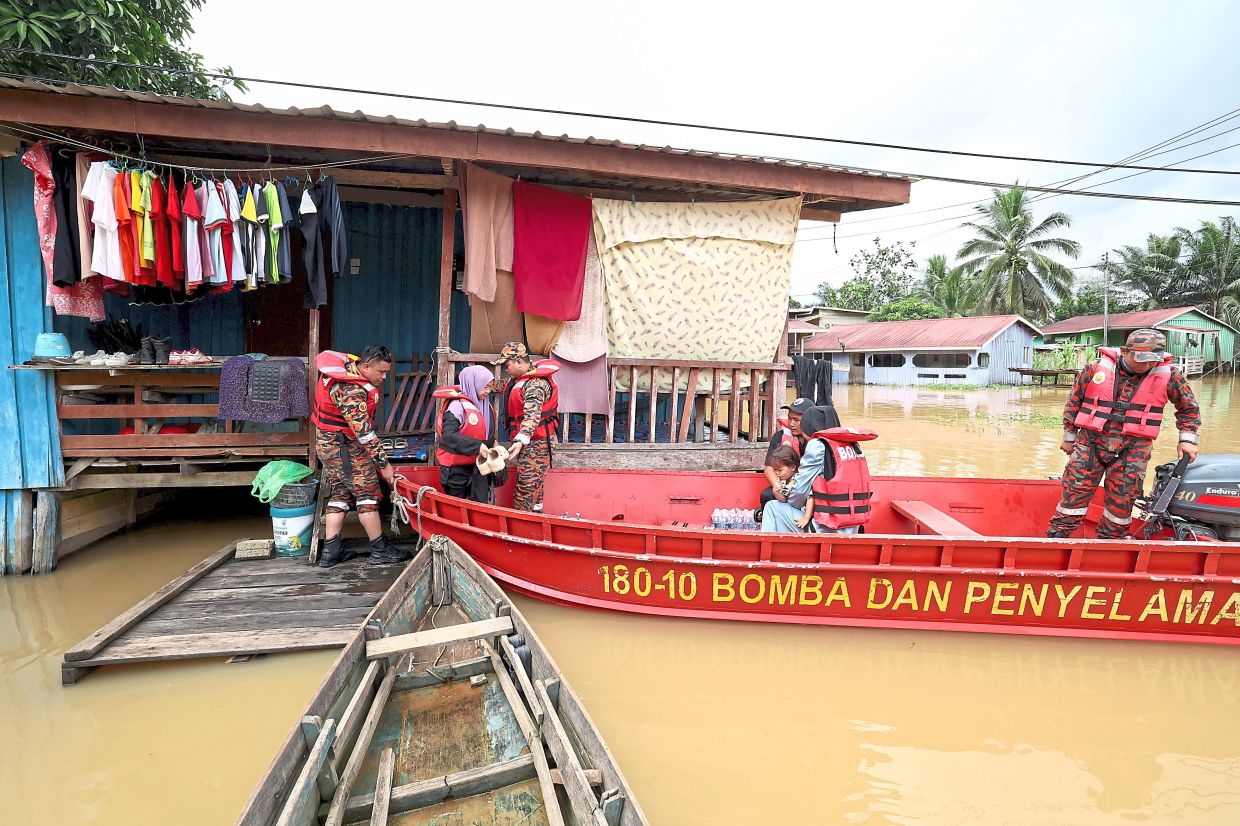 To higher ground: Fire and Rescue Department personnel evacuating flood victims from Kampung Muhibbah to a temporary evacuation centre in Bukit Garam. — Bernama