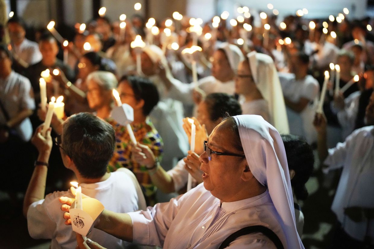A Catholic nun joins others as they hold candles while offering prayers for the country and also victims of the recent earthquake in Myanmar after a religious procession in observance of lent, in Quezon city, Philippines Friday, April 4, 2025. -- AP Photo/Aaron Favila